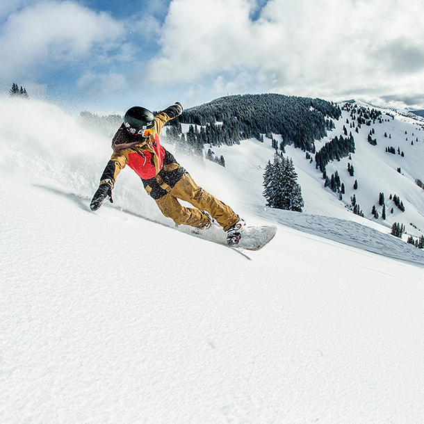 Snowboarder going downhill on snowy mountain